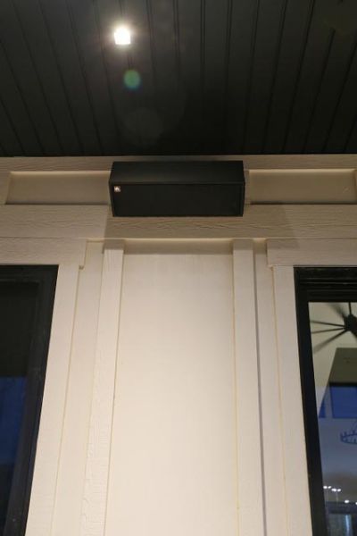 Outdoor wall-mounted speaker installed under a roof overhang, blending with the exterior decor.