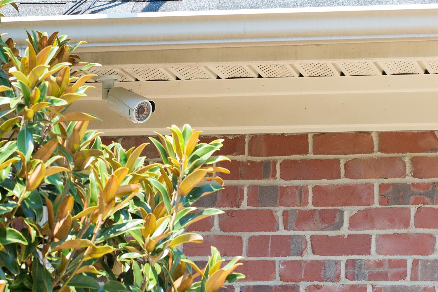 A security camera mounted under the eaves of a house, providing outdoor surveillance.