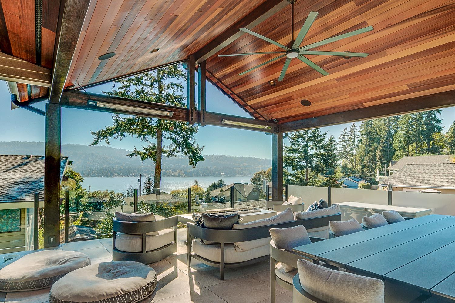 An elegant outdoor patio with a stunning view, featuring a ceiling fan and patio heaters.