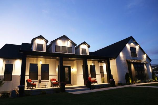 A spacious, well-lit house exterior with multiple peaks and a welcoming entrance, photographed at dusk.