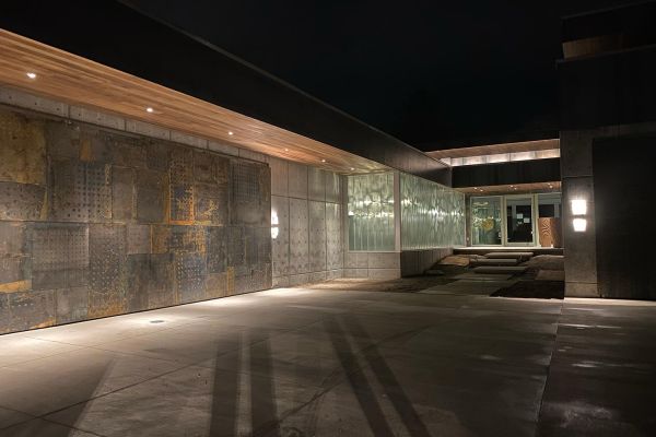 Night view of a contemporary house entrance with a well-lit driveway and modern architectural elements.