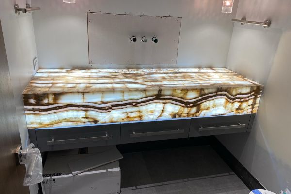 An illuminated translucent stone vanity countertop with a striking pattern, awaiting installation in a bathroom.