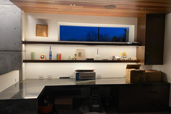 A cozy room with wooden shelves displaying various decorative items and a large desk with boxes and a few unpacked items.