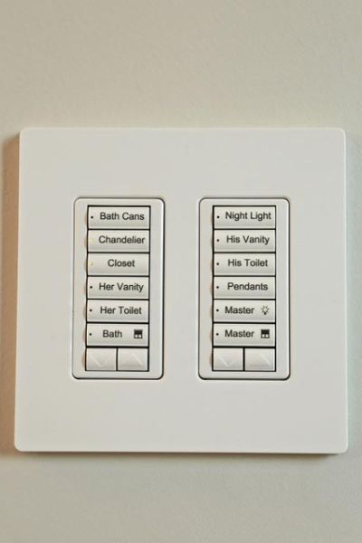 A wall-mounted control panel with labeled buttons for various lighting and fan settings in a bathroom.