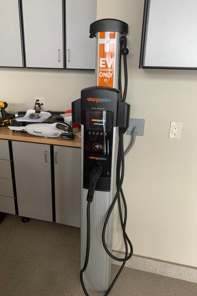 Electric vehicle charging station mounted inside a garage, with a cable and charging plug attached.