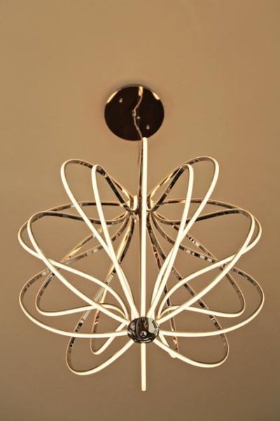 A unique chandelier with intertwined loops of light, resembling an abstract flower, suspended from a ceiling.