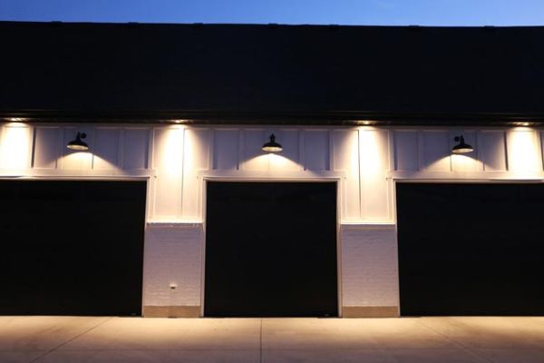 Three-car garage at night with exterior lights illuminating the doors.