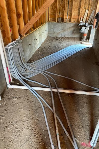 Construction site with multiple PVC conduits laid out for electrical wiring.