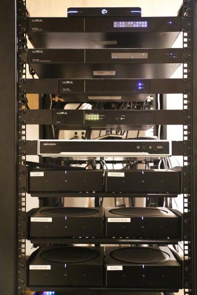 Equipment rack filled with multiple network and audio components, neatly organized and stacked.