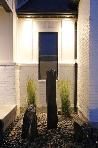 An outdoor area with a modern water feature and accent lighting highlighting the landscape.