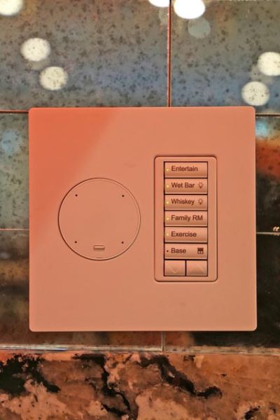 A control panel with buttons labeled for various lighting and entertainment settings in a home bar area.